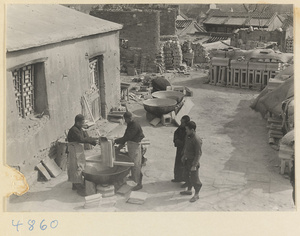 Men glazing roof tiles over a vat at a tile and brick factory near Mentougou Qu