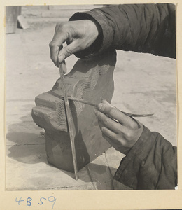 Man measuring a roof ornament at a tile and brick factory near Mentougou Qu