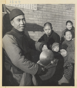 Puppeteer striking gongs called luo (larger) and tang luo (smaller) to attract an audience for a puppet show