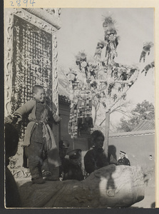 Boy standing on a tortoise stela and street vendor hawking toys at New Year's