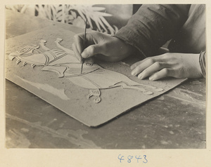 Man cutting a figure of a horse to use for a wallpaper pattern