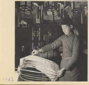 Man laying cloth over the ribs of a lantern in a lantern-making shop