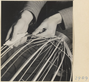 Man tying the ribs of a lantern with string in a lantern-making shop