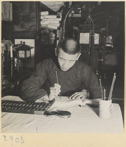 Man with an abacus writing in an account book in a lantern-making shop