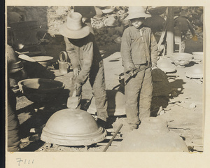 Boys removing an iron pot from a mold at a foundry near Mentougou Qu