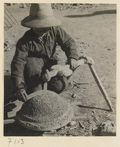 Man working on a mold for an iron cooking pot at a foundry near Mentougou Qu