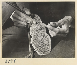 Man holding a pipe and a pipe bag embroidered with characters and swastikas