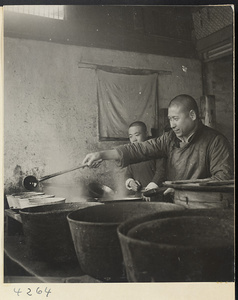 Restaurant interior showing an assistant watching a chef seasoning food