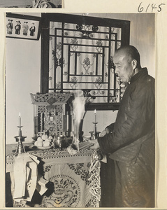 Man lighting incense at a household altar at New Year's