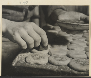 Man stamping moon cakes with characters in a bakery