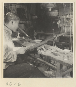 Man smoothing a comb with a plane in a horn-comb workshop