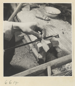 Man using a saw to cut teeth into a comb in a horn-comb workshop
