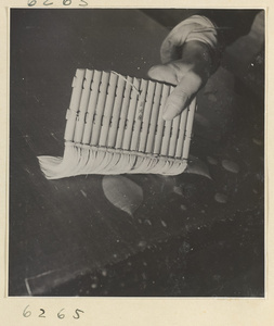 Interior of a scroll-mounting shop showing a man using a soft brush to remove air bubbles