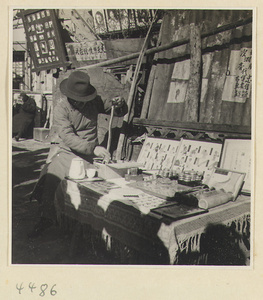 Street doctor holding a snake at his stand displaying medicines and posters picturing ailments