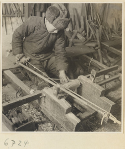 Carpenter turning a piece of wood at a lathe