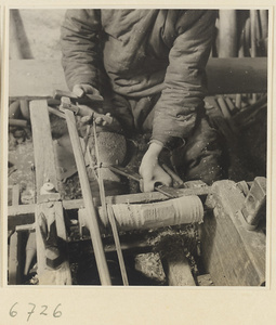 Carpenter turning a piece of wood at a lathe