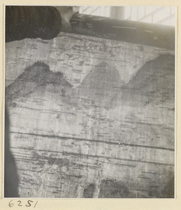 Interior of a scroll-mounting shop showing a man viewing repairs to an unmounted scroll painting by holding it up to a window