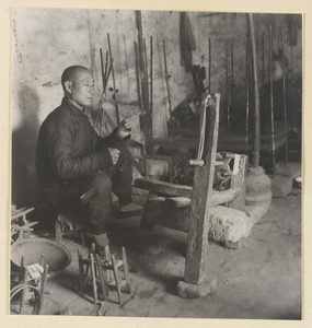 Man spinning silk in a workshop