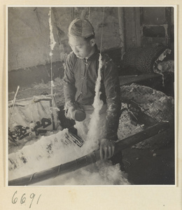 Man preparing cotton for spinning in a workshop