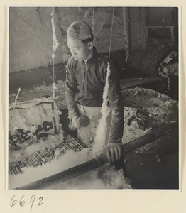Man preparing cotton for spinning in a workshop