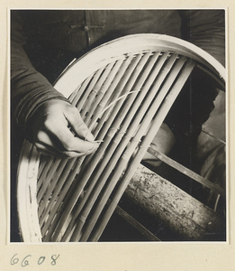 Man securing slats in a bamboo steamer in a workshop