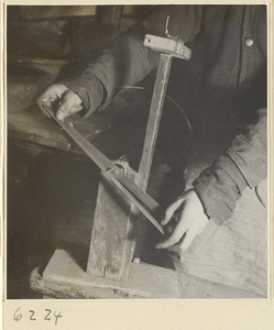 Interior of copper-net factory showing a man holding a shuttle