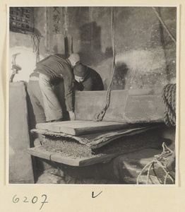 Tobacco shop interior showing men operating a tobacco press