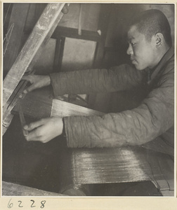 Interior of copper-net factory showing a man working at a loom