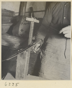 Interior of copper-net factory showing a man winding copper wire from a spool onto a shuttle