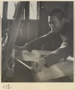 Interior of copper-net factory showing a man working at a loom