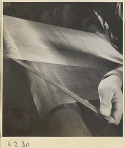 Interior of copper-net factory showing a man working at a loom