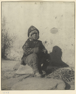 Child dressed in winter clothes sitting outdoors