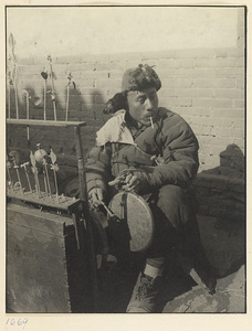 Candy vendor with display of candy forms striking a gong called a luo or qiu tang ren di to attract customers to his stand