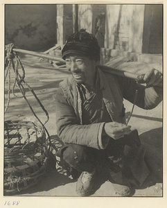Rag and bone dealer sitting with baskets suspended from a shoulder pole and playing a small drum called a xiao gu