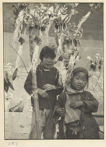 Two girls standing next to hawker's display of paper butterflies