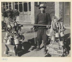 Street vendor with household goods for sale hanging from a shoulder pole