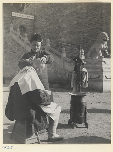 Street barber shaving a customer's head