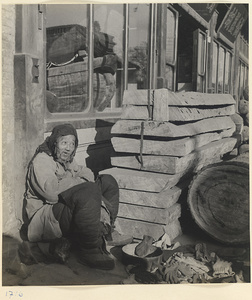 Man hawking gloves next to wooden planks outside a coffin shop