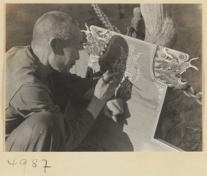 Daoist priest from East Peak Temple decorating a dragon-headed board with shou, the character for longevity, on Hua Mountain