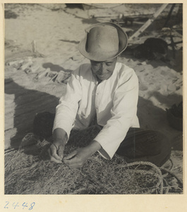 Man repairing nets in a fishing village on the Shandong coast