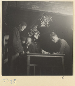 Three men at a table below deck on a junk on the Shandong coast