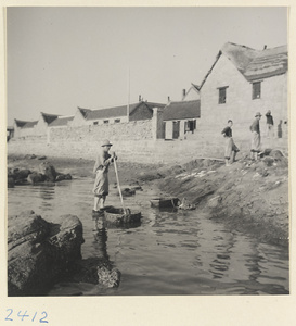 Men with baskets along the shore of a fishing village on Shandong coast