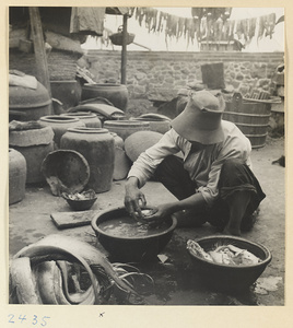 Man at work amidst buckets and vessels in a fishing village on the Shandong coast