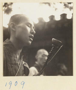 Buddhist monk playing a handchime during a funeral service