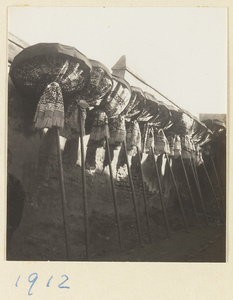 Umbrellas for a funeral procession tied and resting against a wall