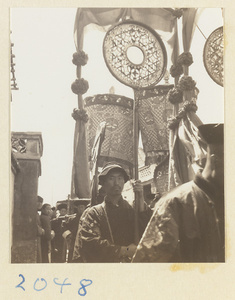 Members of a wedding procession carrying draped mirrors and umbrellas