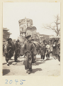 Members of a wedding procession carrying umbrellas, musical instruments, fan-shaped screen, and sedan chair