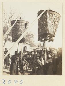 Members of a wedding procession carrying umbrellas and a sedan chair