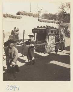 Members of a wedding procession carrying a sedan chair