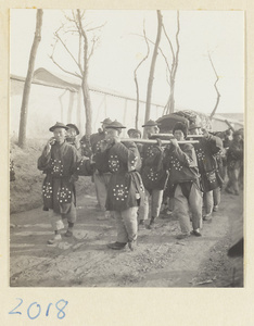 Coffin-bearers carrying a simple coffin in a funeral procession